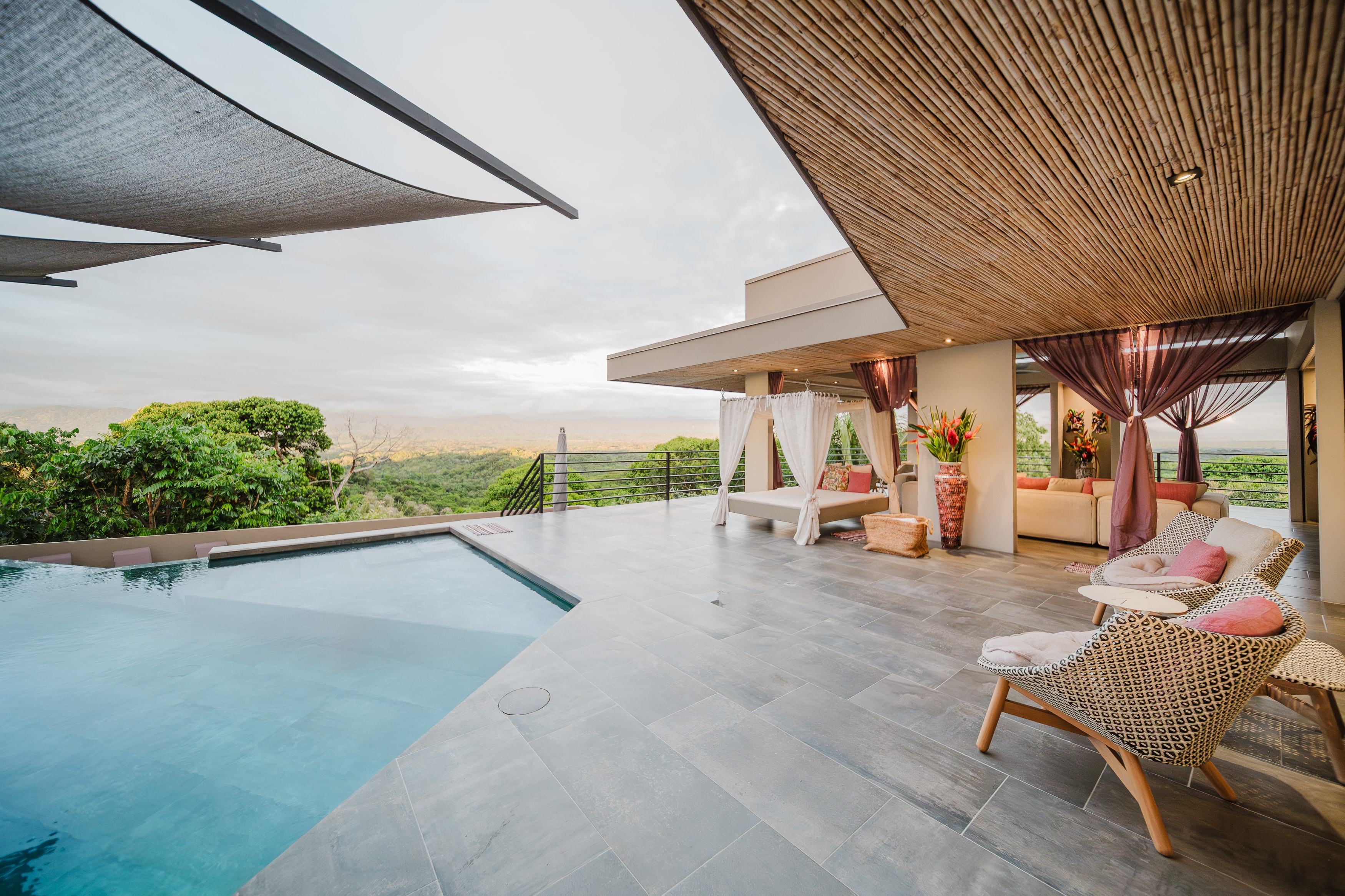 The bamboo ceiling and shade sails over the pool terrace at golden hour